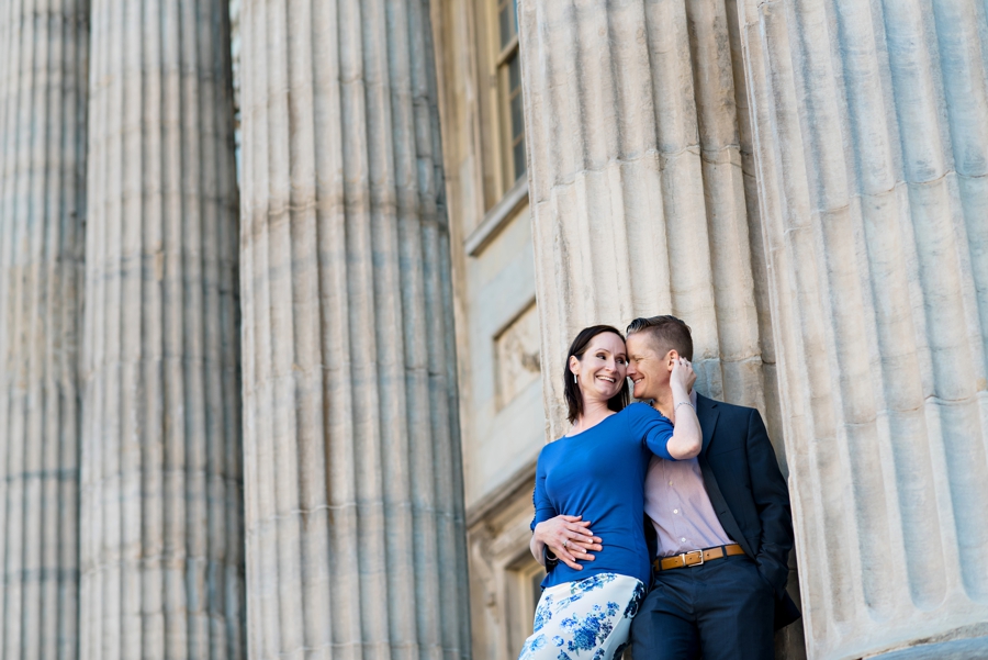 A sexy couple leans against the columns of the first bank of america in philadelphia.